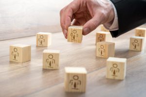 Customer-Managed Relationship Concept - Businessman Arranging Small Wooden Blocks with Symbols on the Table.