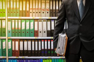 businessman holding data files on binder shelves background