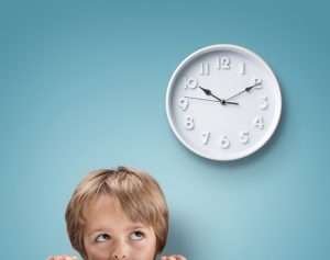 Young boy looking up at a clock concept for deadline, anxiety and stress