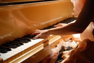 A piano recital, wearing a woman wearing a pink dress is play the piano