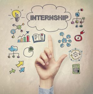 Hand pointing to Internship concept on light brown wall background