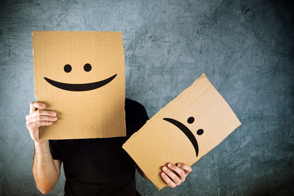 Man holding cardboard paper with happy smiley face printed on. Happiness and joy concept.